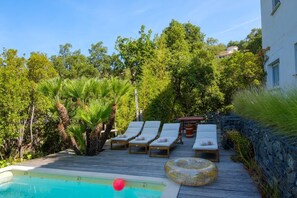 A poolside area with lounge chairs and a wooden deck. - The Villa Under the Stars – Les Issambres (Roquebrune-sur-Argens)
