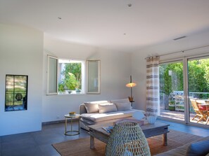 Ein modernes Wohnzimmer mit einer Couch, einem Couchtisch und Blick ins Freie durch große Fenster.