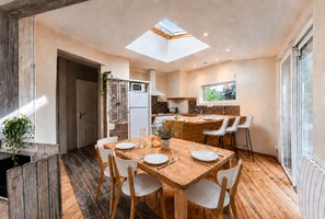 A modern kitchen with a skylight, wooden dining table, and white chairs. - Cozy house near the beach and Arcachon town centre (Arcachon)