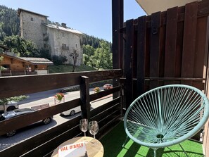 Een balkon met uitzicht op een berg, een houten omheining en een groene stoel.
