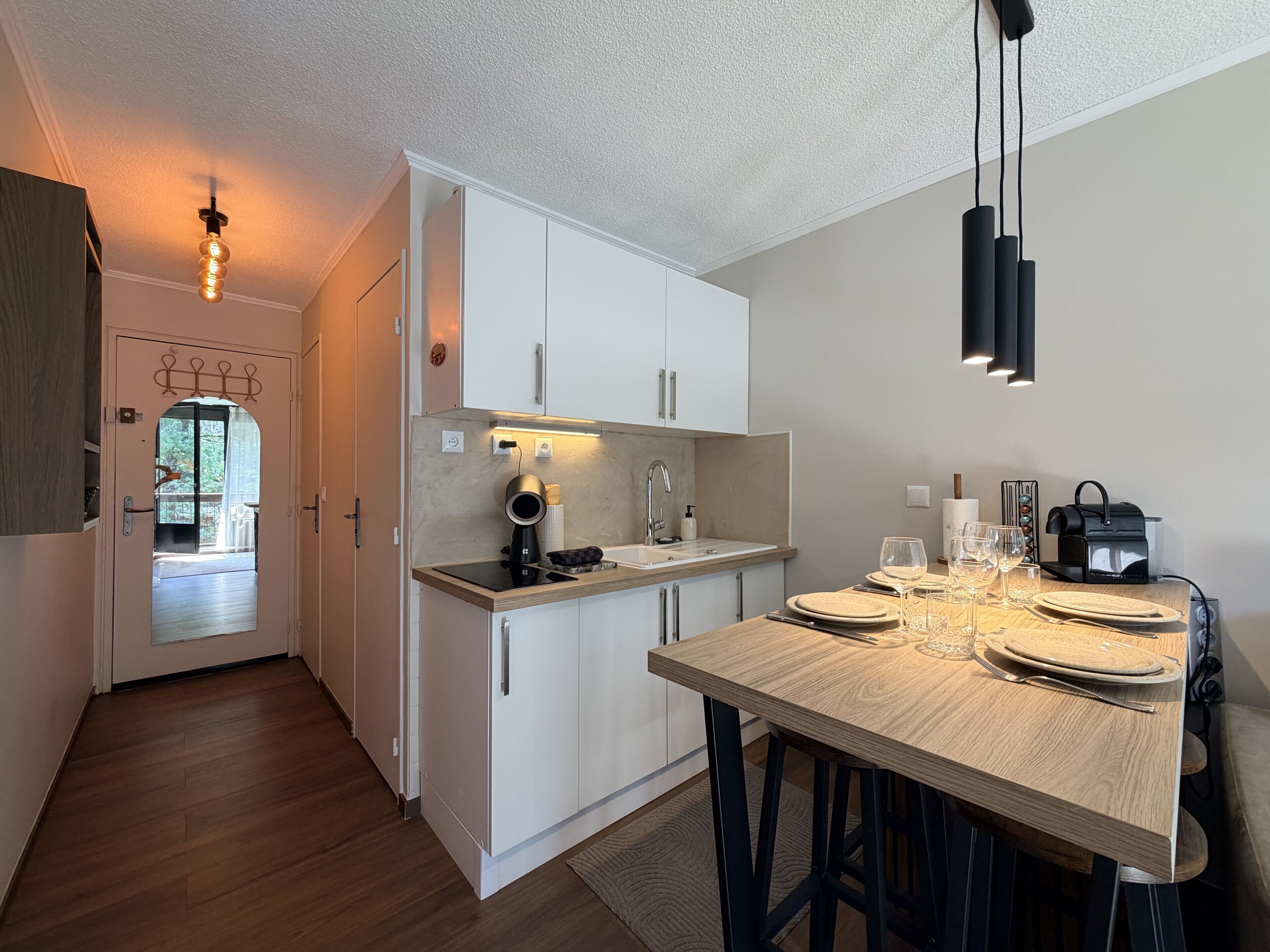 Una cocina moderna con armarios blancos, una mesa de comedor de madera y un horno empotrado.