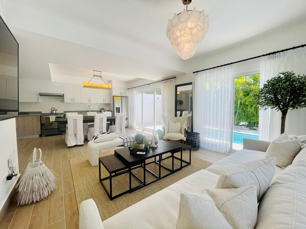 A modern living room with a sofa, coffee table, and a dining area with chairs.