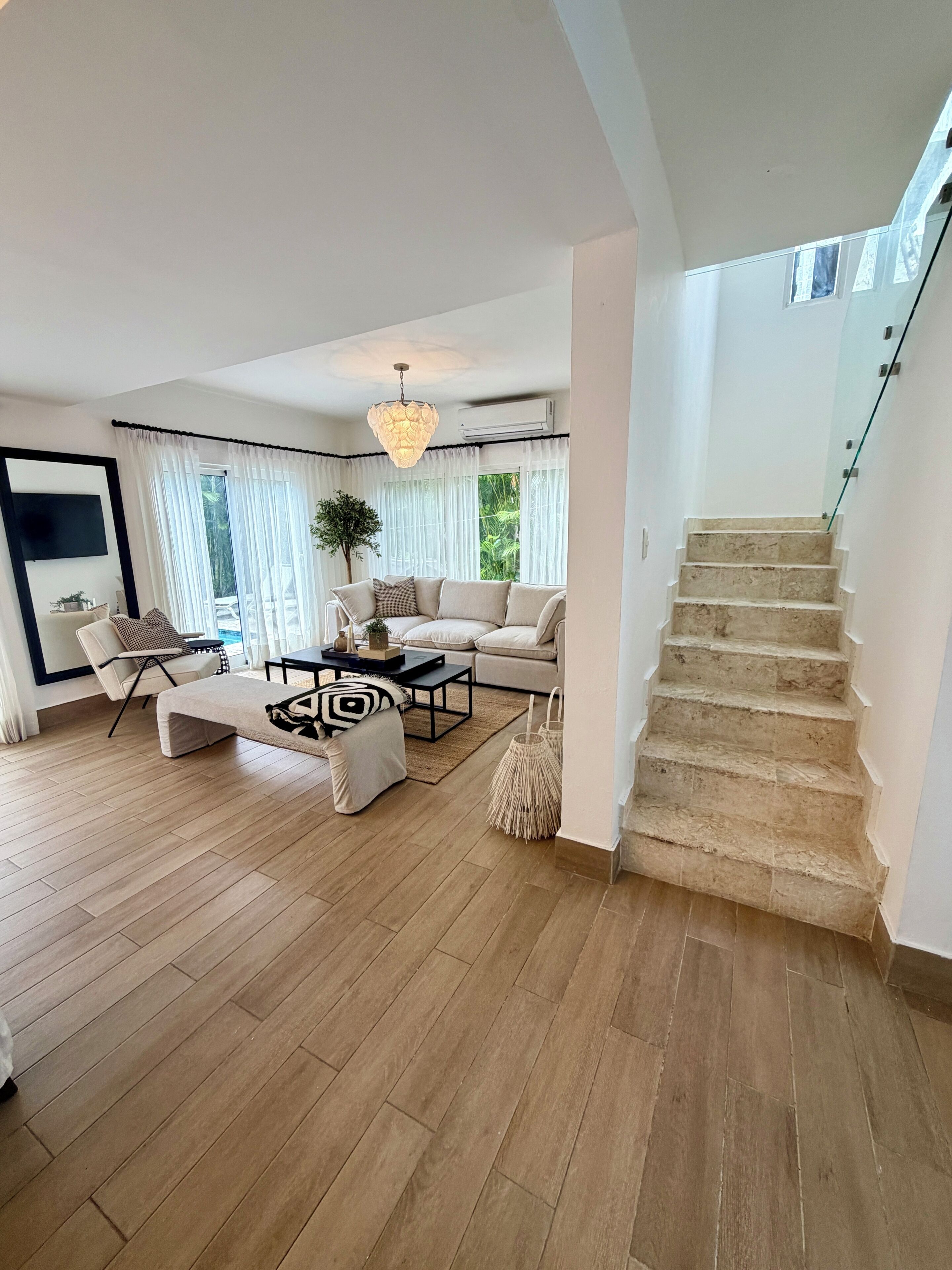 Amplia sala de estar con sofá, mesa de centro y una escalera que conduce a un piso superior.