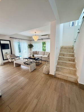 A spacious living room with a sofa, coffee table, and a staircase leading to an upper floor.