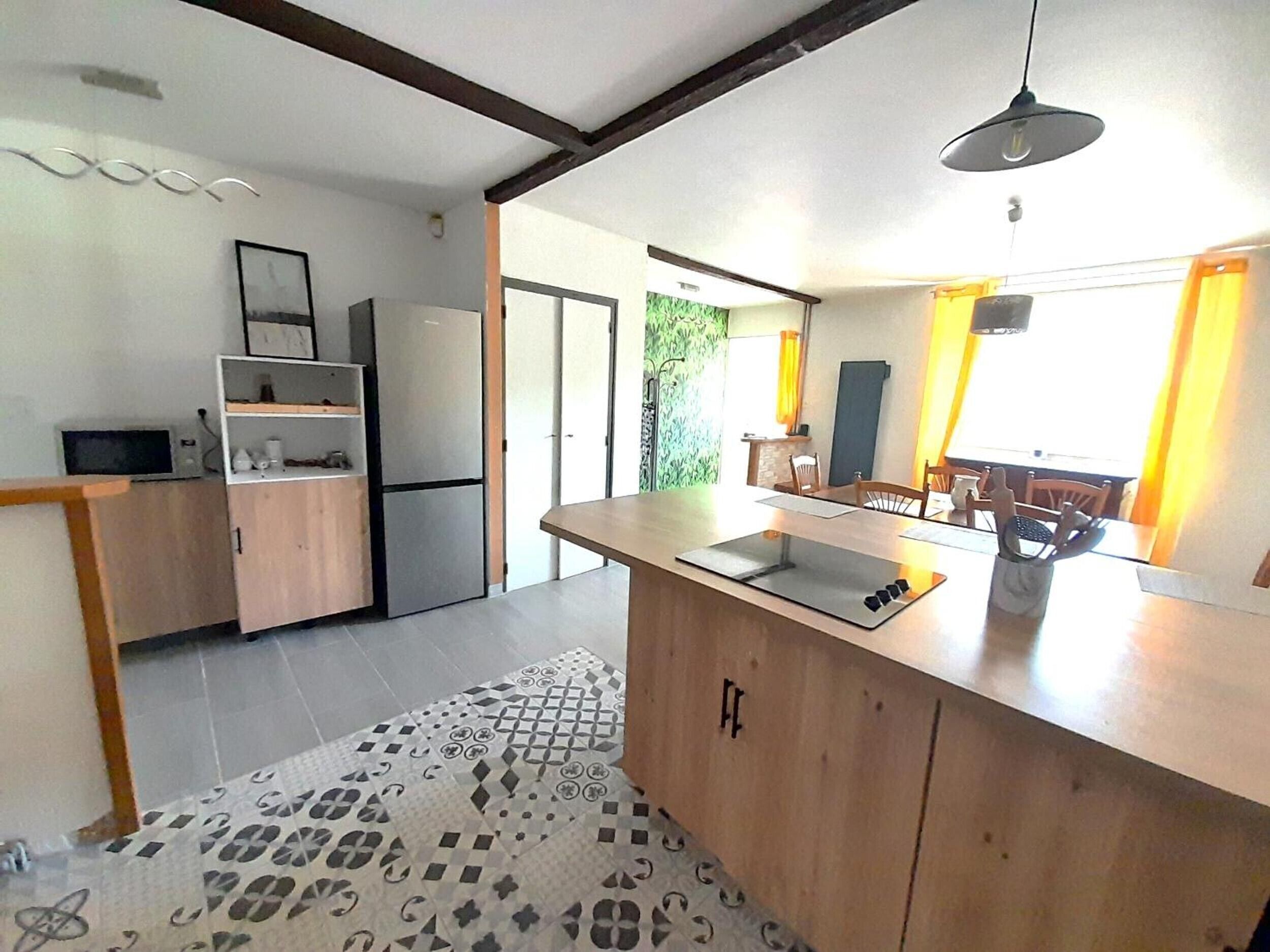 A kitchen with a wooden countertop, a refrigerator, and a dining area with chairs and a table.
