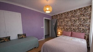 Una camera da letto con un letto, due comodini, un armadio e una porta che dà su un'altra stanza.