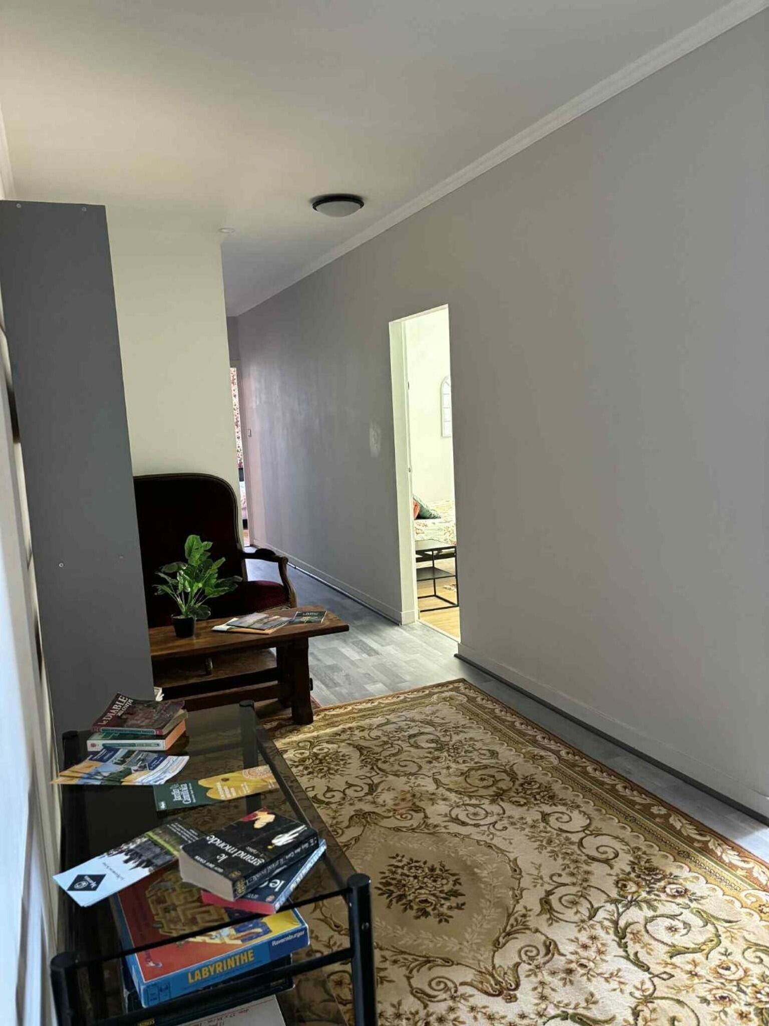 A hallway with a wooden bench, a small table with books, and a patterned rug.