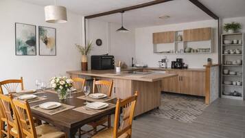 Una cucina moderna con mobili in legno, un'isola centrale e un'area pranzo con sedie e tavolo imbanditi per quattro persone.