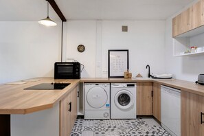 A compact kitchen with a microwave, toaster, sink, and a washing machine.