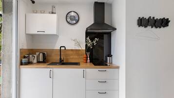 A modern kitchen with a black range hood, a clock, and a minimalist design.