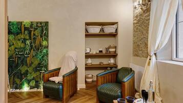 A room with two leather chairs, a wooden floor, a shelf with baskets, and a wall with a textured pattern.