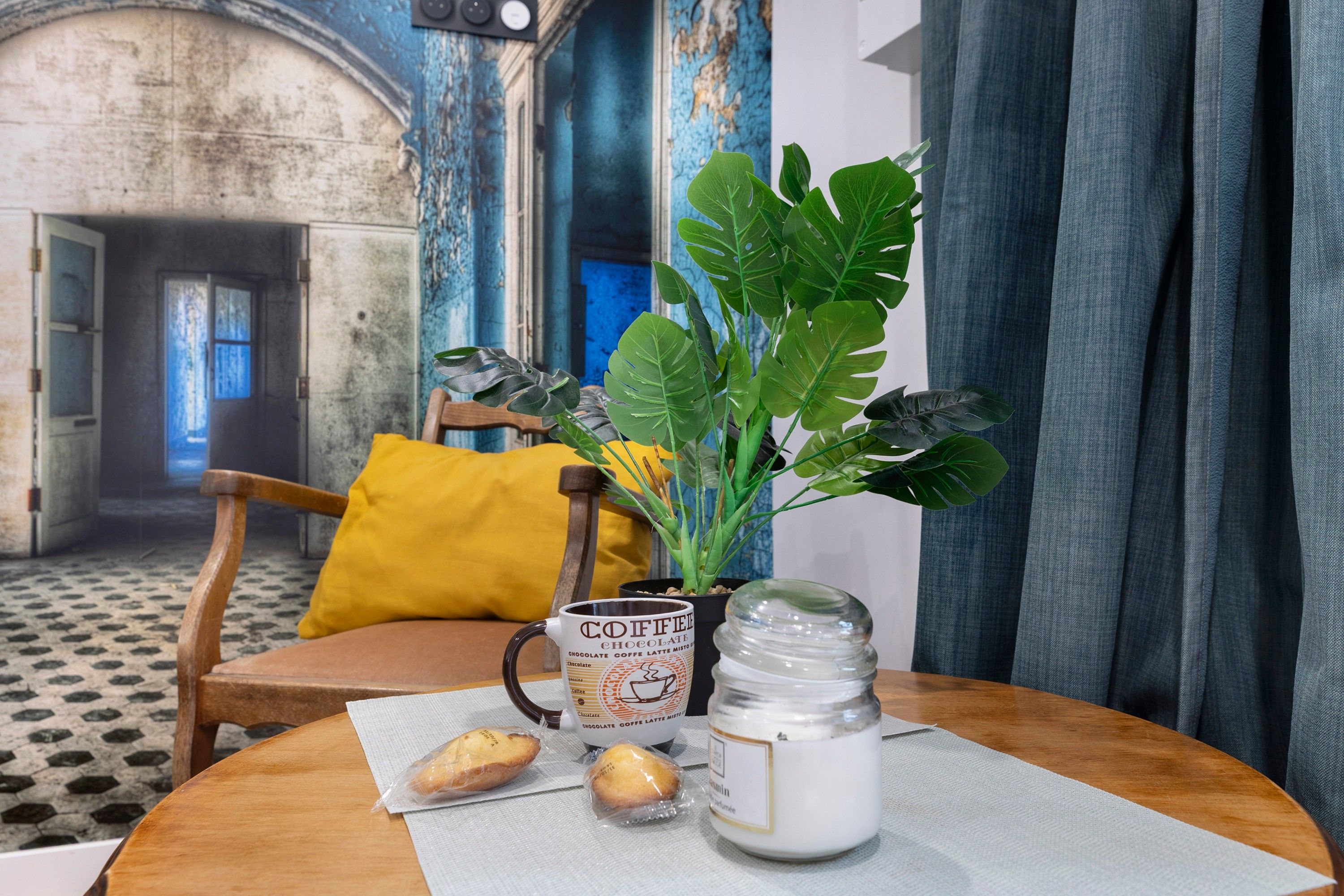 Una mesa con una taza, un tarro y una planta.