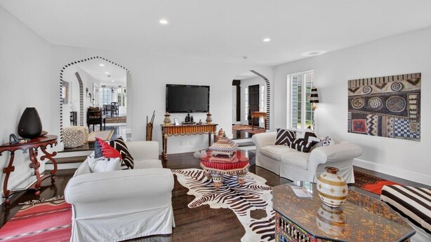 Ein stilvolles Wohnzimmer mit einer Couch, Sesseln, einem Couchtisch und einem Fernseher.