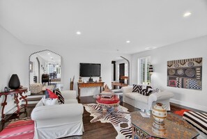 A modern living room with a sofa, armchairs, a coffee table, and a TV. - Modern Cottage Overlooking Sheepscot River (Boothbay)