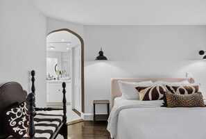 A bedroom with a bed, a nightstand, a lamp, and a mirror. - Modern Cottage Overlooking Sheepscot River (Boothbay)