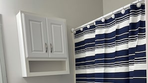 Ein Badezimmer mit einer weißen Toilette, einem weißen Schrank und einem gestreiften Duschvorhang.