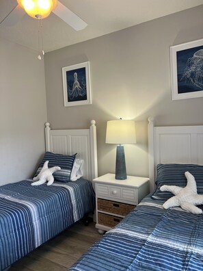 Ein Schlafzimmer mit zwei Betten, einem Nachttisch mit Lampe und Wandbildern.