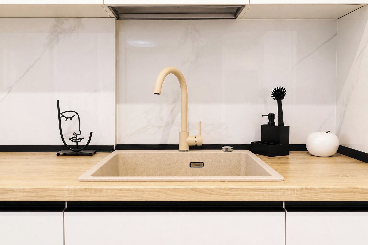 Et moderne køkken med en beige vask, en sort hane og et minimalistisk design.