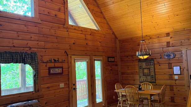 A cozy cabin interior with a dining area, a sofa, and a ceiling fan.