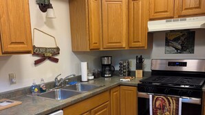 A kitchen with wooden cabinets, a stainless steel stove, a dishwasher, and a coffee maker.