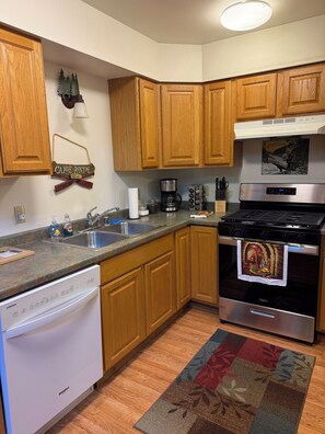 A kitchen with wooden cabinets, a stainless steel stove, a dishwasher, and a coffee maker.