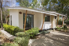 A single-story building with a flat roof, large windows, and a covered outdoor area. - Eco Casita 1.8 in Hacienda Iguana (Tola)