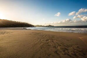 A beach with sand, waves, and a forested area. - Eco Casita 1.8 in Hacienda Iguana (Tola)
