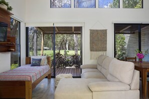 Een modern interieur met een bed, een bank en een eethoek met uitzicht op het omliggende landschap.