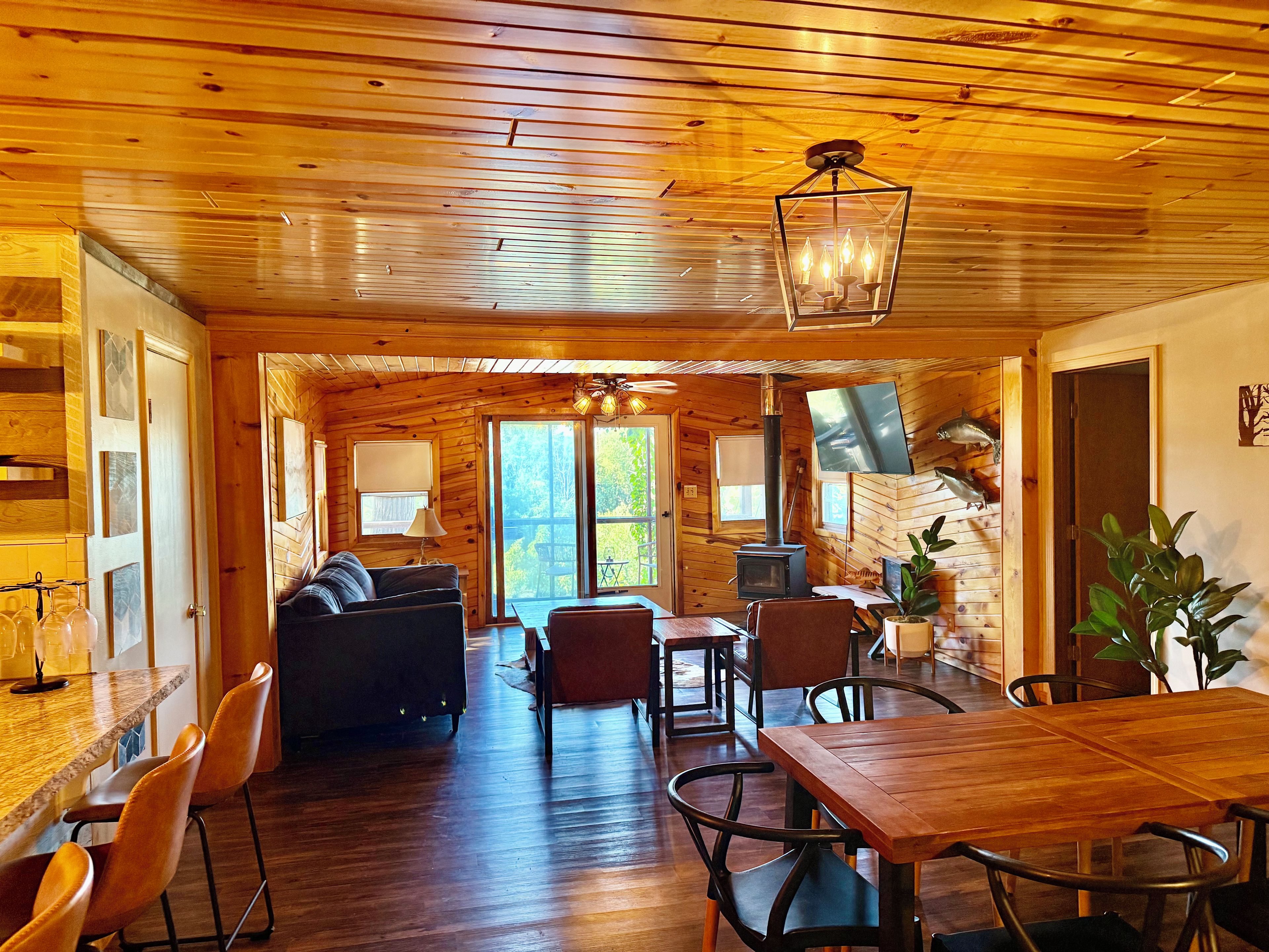 A cozy cabin interior with a dining area, a sofa, and a fireplace.