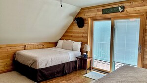 Une chambre confortable avec un plafond en pente, un lit avec une base de couleur marron, une table de chevet avec une lampe et une pancarte sur laquelle on peut lire : « La vie à la cabane ».
