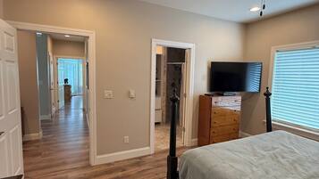Une chambre à coucher avec un lit, un ventilateur de plafond, une télévision et une commode.