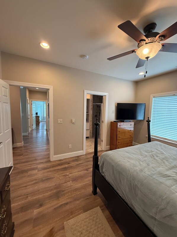 A bedroom with a bed, a ceiling fan, a TV, and a dresser.