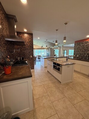 Una cocina moderna con una isla central, muebles blancos y un salpicadero con diseño de mosaico.