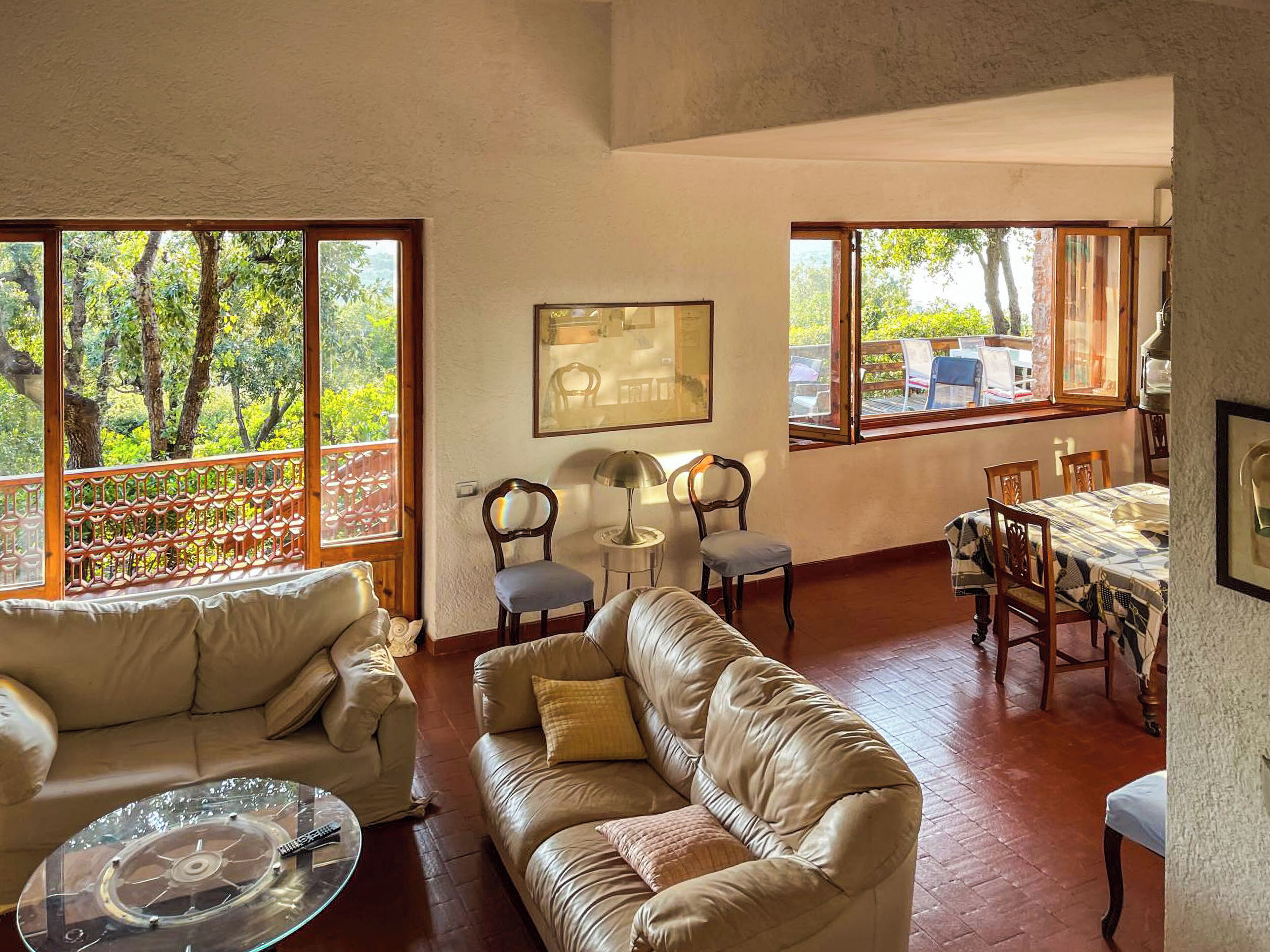 A living room with a sofa, a glass coffee table, and a dining area with chairs and a table.