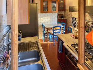 A compact kitchen with a sink, stove, and dining area. - Villa Carra (Ansedonia)