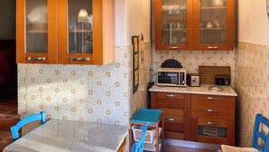 Eine kleine Küche mit Holzausstattung, einer Mikrowelle, einem Toaster und einem Tisch mit Stühlen.