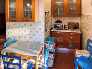 Eine kleine Küche mit Holzausstattung, einer Mikrowelle, einem Toaster und einem Tisch mit Stühlen.