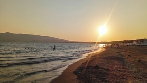 Une plage offrant une vue dégagée sur la mer et les collines lointaines.