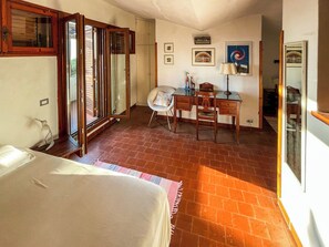 A room with a bed, a desk, a chair, and a window with blinds. - Villa Carra (Ansedonia)