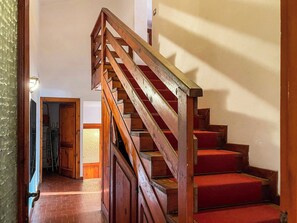 Eine Holztreppe mit roten Teppichstufen, die zu einer oberen Etage hinaufführt.