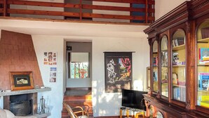 Ein großzügiger Wohnbereich mit Kamin, einer Holztreppe, einem Fernseher und einem Bücherregal.