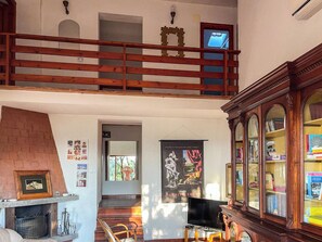 Ein großzügiger Wohnbereich mit Kamin, einer Holztreppe, einem Fernseher und einem Bücherregal.
