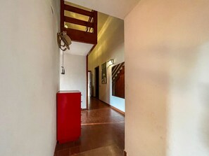 A hallway with a red cabinet, wooden ceiling beams, and a staircase in the distance. - Villa Carra - Ansedonia (Ansedonia)