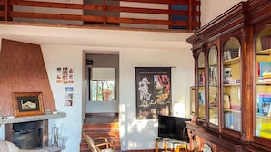 A spacious living area with a fireplace, a television, and a bookshelf. - Villa Carra - Ansedonia (Ansedonia)