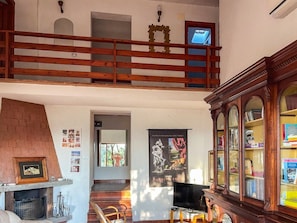 Ein geräumiger Wohnbereich mit Kamin, Fernseher und Bücherregal.