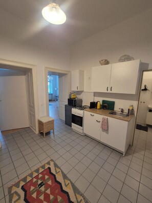 A kitchen with white cabinets, a stove, and a sink. There is a patterned rug on the floor. - Vintage Charm Apartment near Prater & Metro Station (Wien)