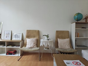 A room with two armchairs, a small round table with a plant, a globe, and a bookshelf.