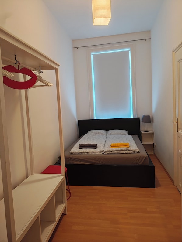 A bedroom with a bed, a wardrobe, a bedside table, and a lamp.