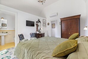 A bedroom with a bed, a dresser, a television, and a wardrobe.