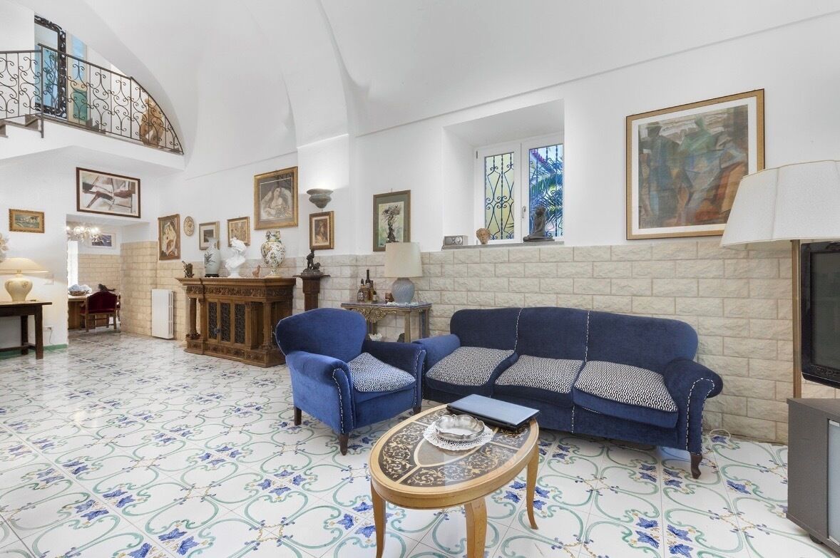 Ein geräumiges Wohnzimmer mit einem blauen Sofa, zwei Sesseln, einem Couchtisch und einem Kamin.